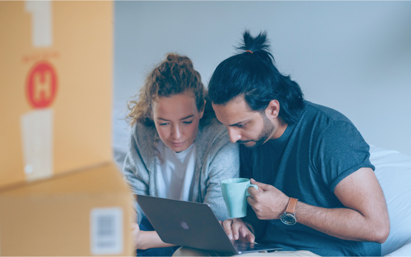 couple next to moving boxes viewing a computer 