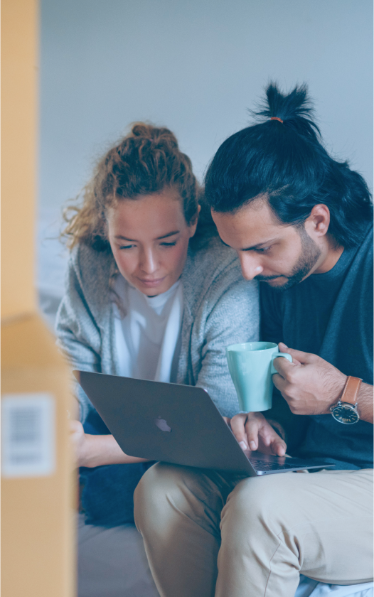 couple next to moving boxes viewing a computer